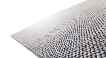 handwoven wool rug with droplet structure in natural colours with dark blue contrast yarn